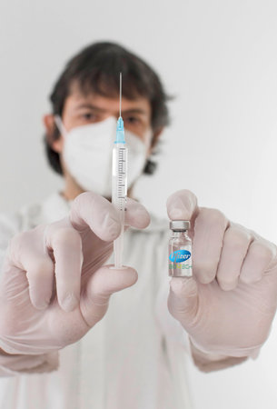Graz,Austria-26.01.2021: Doctor holding a vaccine bottle and syringe, beginning of mass vaccination with the Pfizer-BioNTech COVID-19 vaccine, coronavirus world immunization conceptのeditorial素材