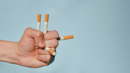 Hand holding many cigarettes and blue background. Stop smoking, World No Tobacco Day on May 31 concept. Selective focusの写真素材