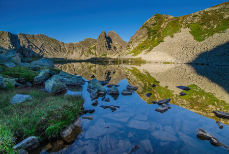 Mountain landscape and glacial Taul Portii lake in Retezat National Park, Carpathian Mountains, Romania, at sunriseの写真素材