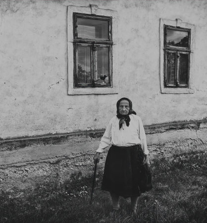 Salaj, Transylvania, Romania-May 14, 2018: very old woman standing alone in front of her old house in countryside. Black and white, vintage moodのeditorial素材