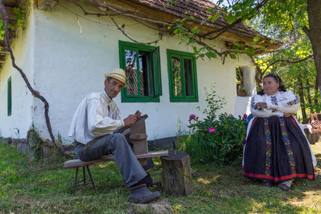 Salaj, Transylvania, Romania-May 14, 2018: old couple, man and wife in traditional Romanian folk costume, working in front of their charming houseのeditorial素材