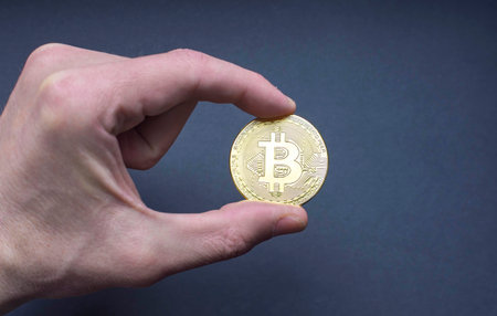Man hand holding a Bitcoin BTC crypto currency gold coin, new virtual money concept. Mining or blockchain technologyの写真素材