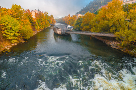 Mur river in autumn, with Murinsel bridge and old buildings in the city center of Graz, Styria region, Austria.のeditorial素材