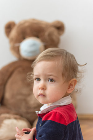 Child playing with his sick teddy bears wearing medical mask against viruses. Role playing, child playing doctor with plush toy. Children and illness concept.の写真素材