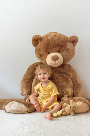 Sweet happy child boy playing with his giant teddy bear, indoor at homeの写真素材