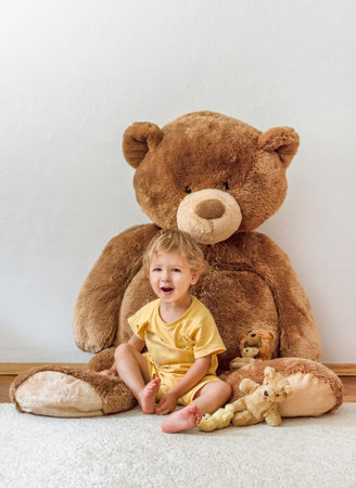 Sweet happy child boy playing with his giant teddy bear, indoor at homeの写真素材