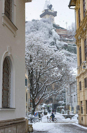 Graz, Austria-December 09, 2021: People walking through heavy snow and the famous Clock Tower in the background, in the city center of Graz, Steiermark, Austria, in winter dayのeditorial素材