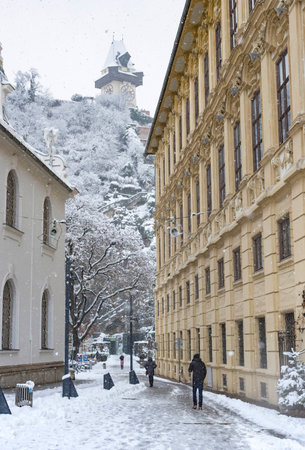 Graz, Austria-December 09, 2021: People walking through heavy snow and the famous Clock Tower in the background, in the city center of Graz, Steiermark, Austria, in winter dayのeditorial素材