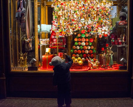 Graz, Austria-December 02, 2021: Little child looking at Christmas glass decorations for sale on a window shopのeditorial素材