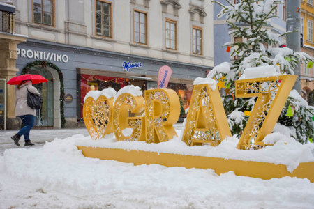Graz, Austria-December 09, 2021: People walking through snow in Main square Hauptplatz, in the city center of Graz, Steiermark, Austria, in beautiful winter dayのeditorial素材