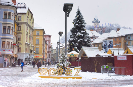 Graz, Austria-December 09, 2021: People walking through snow in Main square Hauptplatz, in the city center of Graz, Steiermark, Austria, in beautiful winter dayのeditorial素材