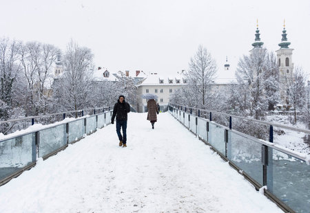 Graz, Austria-December 09, 2021: People walking through the snow and Mariahilfer church in the background, in Graz, Steiermark, Austria, in beautiful winter dayのeditorial素材