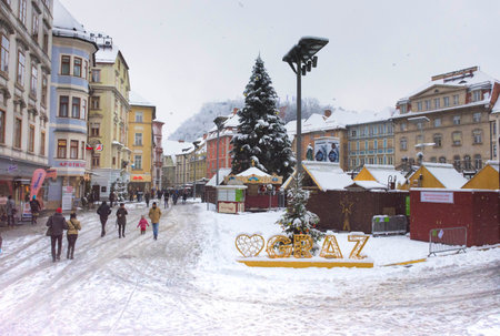 Graz, Austria-December 09, 2021: People walking through snow in Main square Hauptplatz, in the city center of Graz, Steiermark, Austria, in beautiful winter dayのeditorial素材
