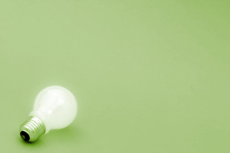 Background with lit lightbulb. Isolated on greenの写真素材