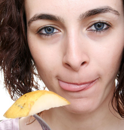Woman eating tasty pear with forch.の写真素材
