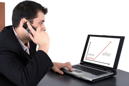 Succesful business man working at laptop and talking at cellphoneの写真素材