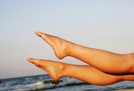 Woman legs tanning on the beachの写真素材