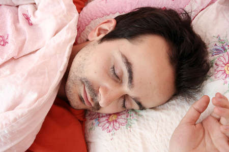 Closeup portrait of a young man sleeping on the bed .の写真素材