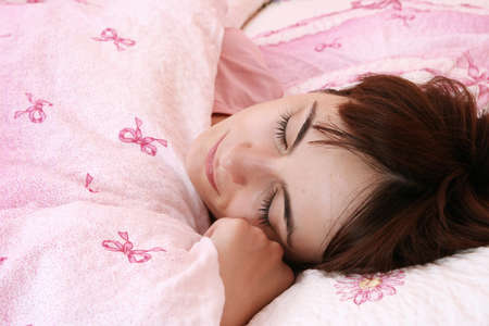 Beautiful young woman sleeping on bed in her bedroom at home in the morning.の写真素材