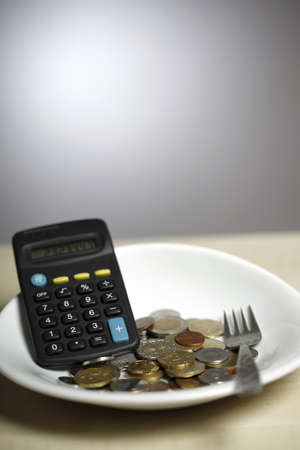 Many coins on a white plate and a forkの写真素材