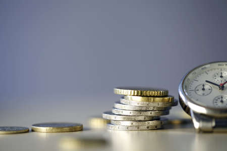Time and Money - close up of one clock and some euro coins