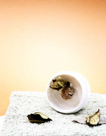 Spa essentials (cream, white towel and flowers) isolated on yellowの写真素材