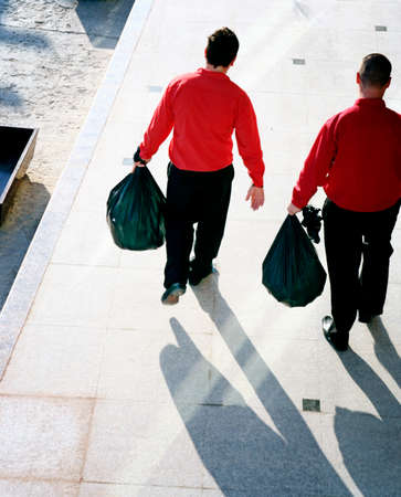 Two men taking out the garbage.の写真素材