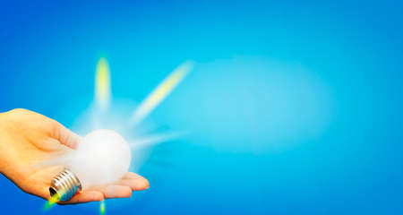 Background with lit lightbulb. Isolated on blueの写真素材