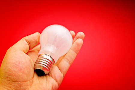 Background with lit lightbulb. Isolated on redの写真素材