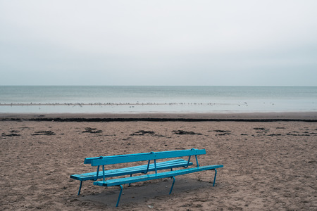 Baltic sea beach with a wooden blue bench in winterの写真素材