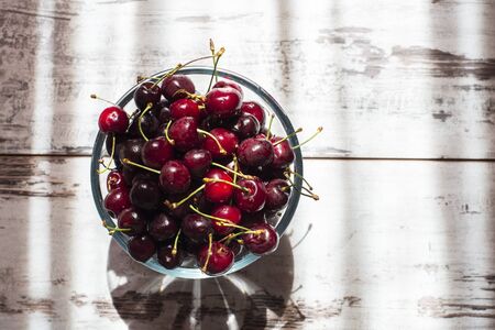 Dark red sweet cherries in transparent bowl top viewの写真素材