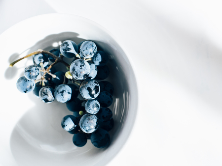 Merlot grape vine in white porcelain bowl on white tableの写真素材