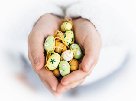 Hands of girl in white jumper holding colorful Easter eggs decorationの写真素材