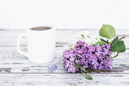 Black tea in white cup on wooden table with vintage branch of lilacの写真素材