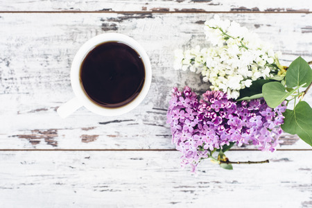 Black tea in white cup on wooden table with vintage branch of lilac top viewの写真素材