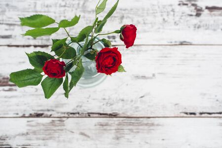 Glass vase with bouquet of roses on vintage tableの写真素材