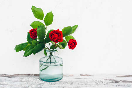Glass vase with bouquet of roses on vintage tableの写真素材