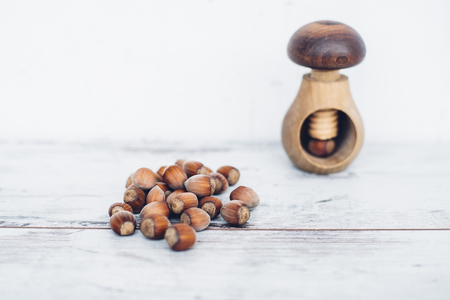Hazelnuts in pile on wooden table with one mushroom-shaped nut in the nut-crackerの写真素材