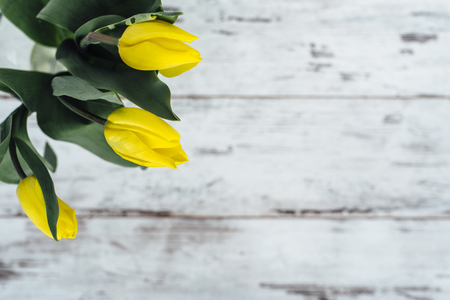 Yellow tulips in vase on wooden tableの写真素材
