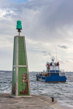 Beacon and anchored dredger boat in Carril port