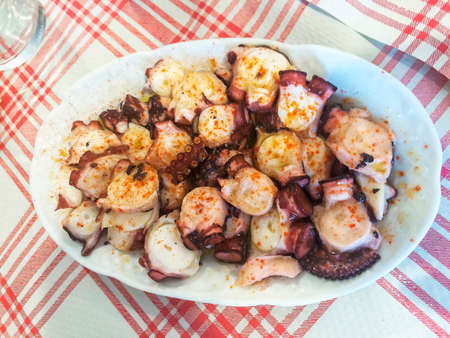 Tray with pieces of octopus tentacles on fair sauceの写真素材