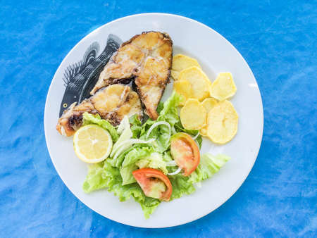 Grilled grouper with potatoes and salad on a plateの写真素材