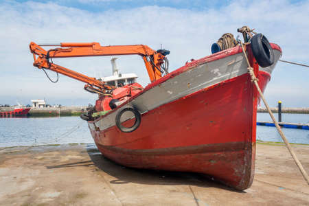 Red boat with a dredger on the ramp of Vilaxoan harbor in Vilagarcia de Arousaの写真素材