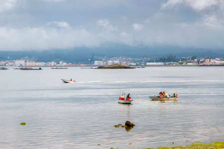 Shellfish fishermen capturing clams from a boat in Sinas beach, Vilanova de Arousaの写真素材