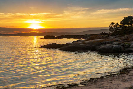 Beach and rocky coast in Arousa Island at sunsetの写真素材