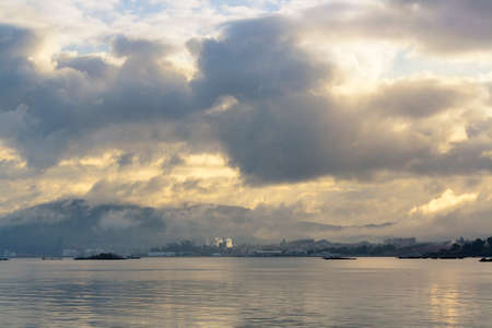 Misty and cloudy dawn on Arousa bay with Curota mount in Vilagarcia de Arousa at backgroundの写真素材