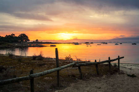 Wooden fence surrounding the coastal dune of Espineiro beach in Arousa Island at golden sunsetの写真素材