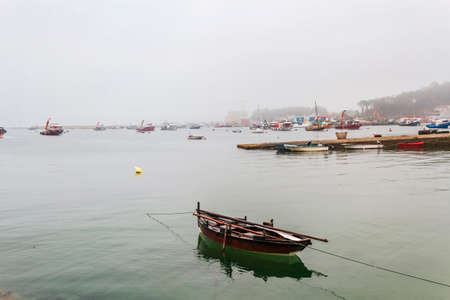 Traditional dorma boat anchored on Illa de Arousa fishing harbor under the fogの写真素材