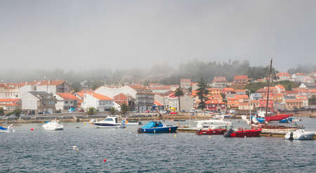 Anchored boats and Illa de Arousa seafront in the fogの写真素材