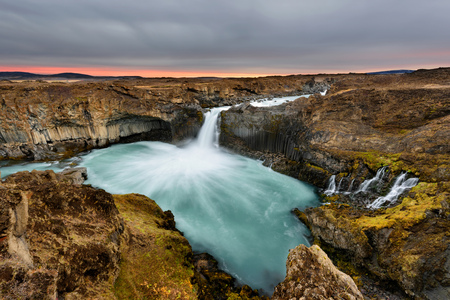 Aldeyjarfoss waterfall in Iceland at sunrise with golden clouds in the sky. Amazing landscape in...